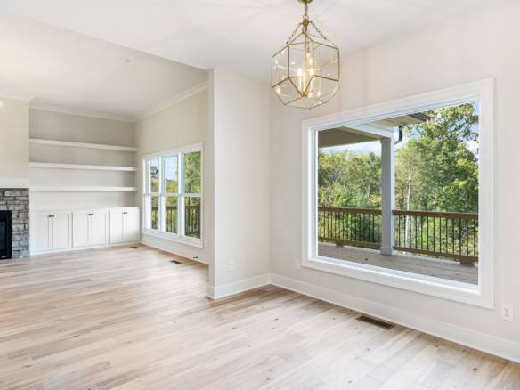 Spacious living area featuring large windows, bright interior, and hardwood flooring in a newly buil.