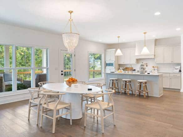Modern kitchen and dining space with large windows, white cabinetry, and a central island.
