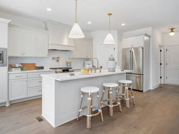 Bright, spacious kitchen with white cabinetry, stainless steel appliances, and a central island.