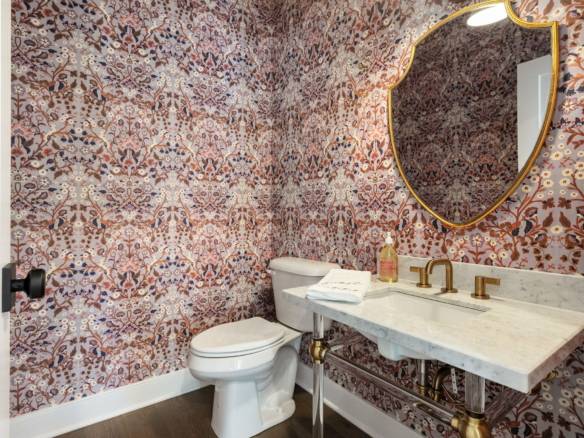 Bathroom with intricate, colorful wallpaper and elegant gold fixtures.