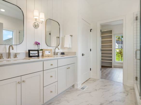 Bathroom with double vanity, mirrors, and walk-in closet in a contemporary home.
