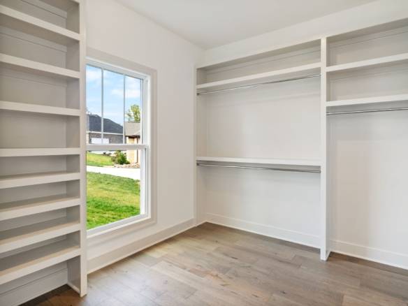 Walk-in closet featuring custom white shelving and ample storage space.