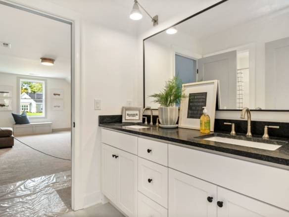 Modern bathroom vanity with black countertop and large mirror.