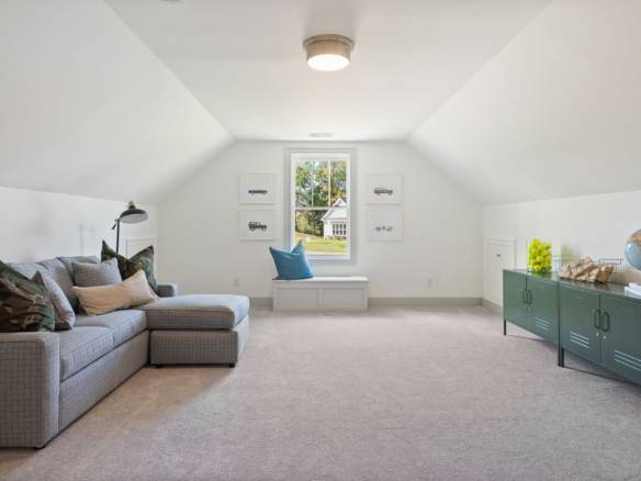 Attic living room with a gray sofa, window seat, and bright decor.