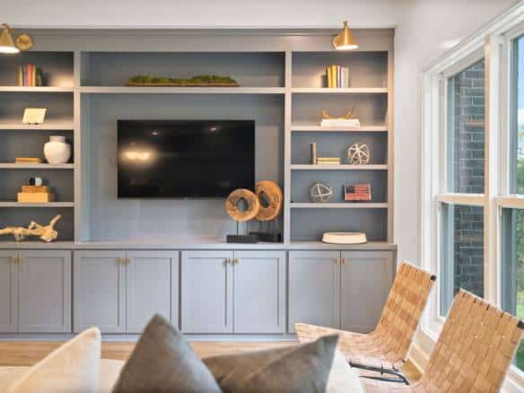 Living room with built-in blue shelving, TV, and natural light from large window.