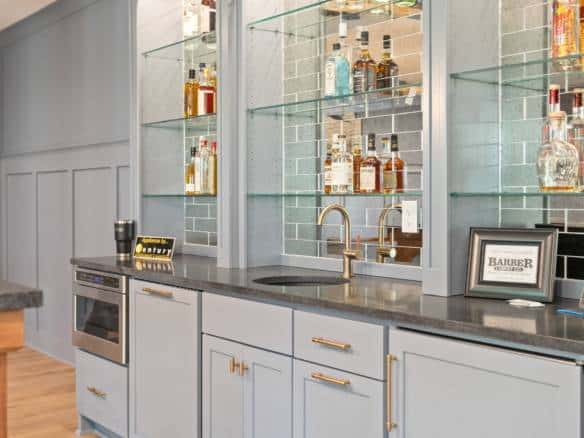 Elegant home bar featuring glass shelving and a sleek countertop.