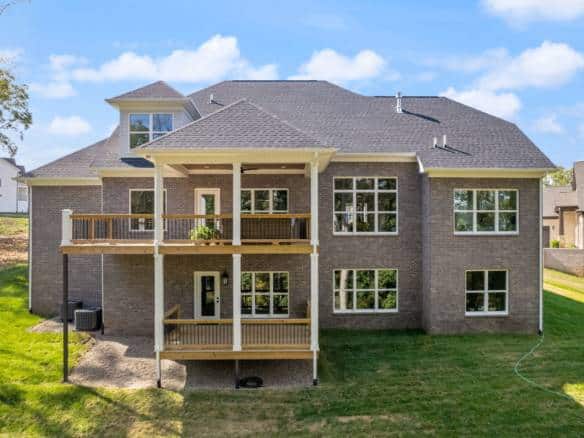 Beautiful brick house with large decks and multiple windows.