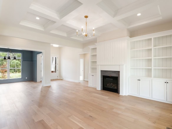 Spacious living room featuring a cozy fireplace and custom built-in white shelves, perfect for famil.