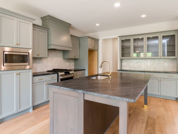 Modern kitchen with gray cabinets, granite countertops, and stainless steel appliances.