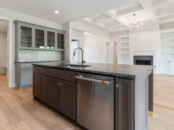 Modern kitchen with island and stainless steel appliances, open to bright living area at 6209 Brentw.