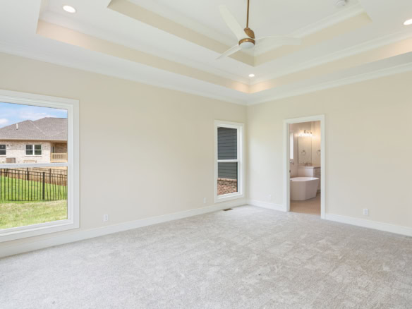 Interior view of a spacious, newly built living room with large windows and a ceiling fan.