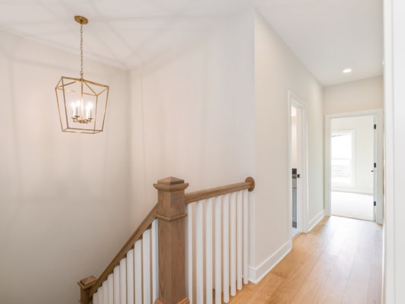 Bright hallway with natural light and elegant wooden staircase railing.