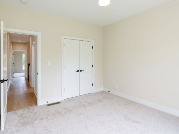 Bright, clean room with beige walls and white closet doors.