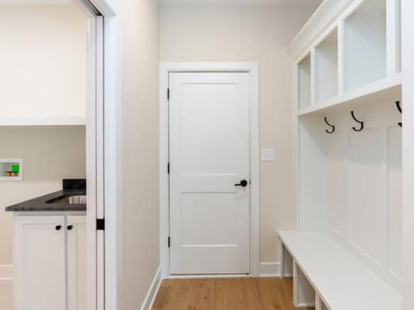 Interior mudroom with white built-in storage bench and hooks for organization.