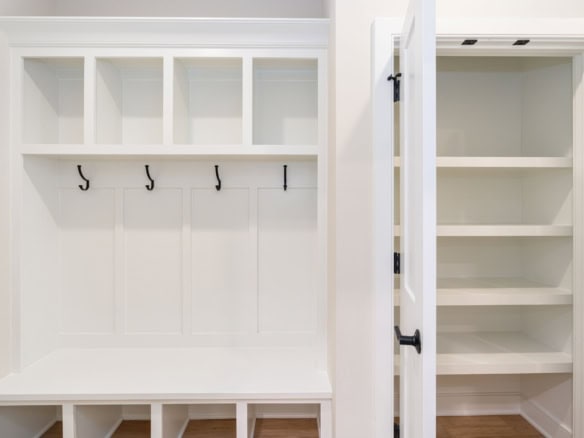 Custom white mudroom with hooks and storage benches for organized entryway.
