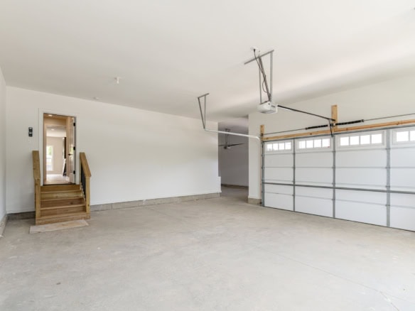 Spacious garage with unfinished concrete floor and large garage door, ideal for parking and storage.