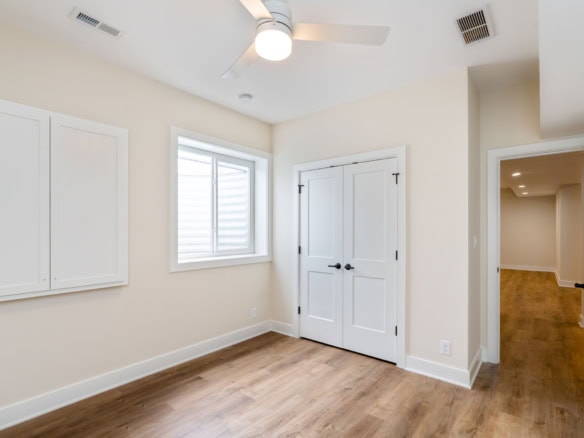 Interior room with white walls, ceiling fan, and hardwood flooring.