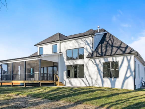 Modern two-story house with a spacious deck and large windows.