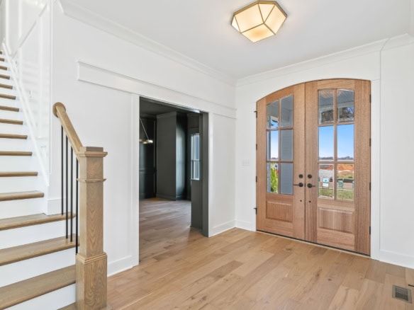 Entryway with double wooden doors and natural light.