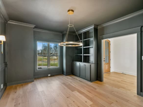 Interior view of a modern living room with built-in shelves and large windows.
