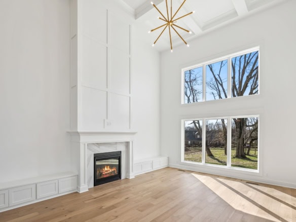 Modern white living room featuring a cozy fireplace and large windows overlooking a garden.