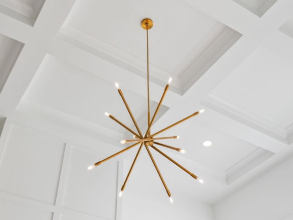 Modern gold chandelier in a new home with a coffered ceiling.