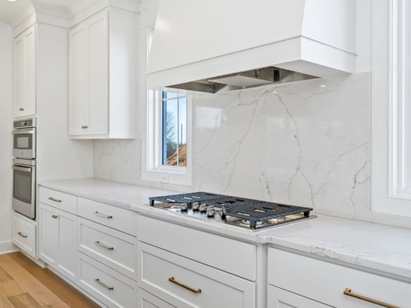 White kitchen with marble backsplash and built-in gas stove for a sleek, contemporary look.