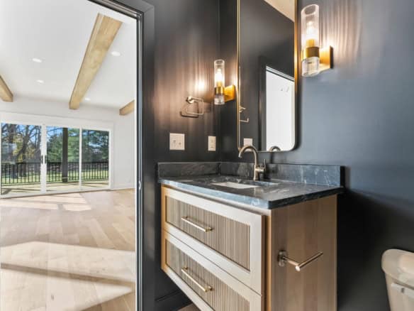 Modern bathroom featuring a dark accent wall, sleek vanity with marble countertop, and contemporary.