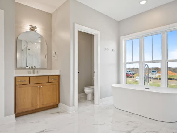 Bathroom with a freestanding tub, vanity, and bright natural light from large windows.