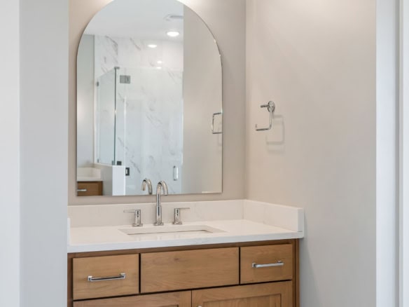 Modern bathroom vanity with wooden cabinet and large mirror.