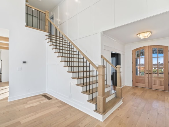 Elegant wooden staircase with open risers in a bright, spacious home.