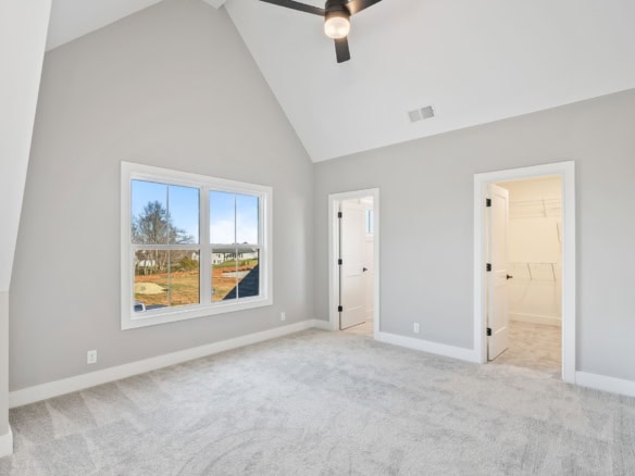 Bright, spacious bedroom with vaulted ceiling and large window.