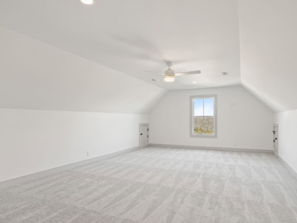Attic room with white walls, carpeted floor, and a window overlooking the outdoors.