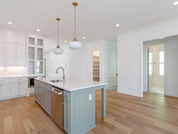 Modern kitchen featuring white cabinetry, a central island, and hardwood floors.