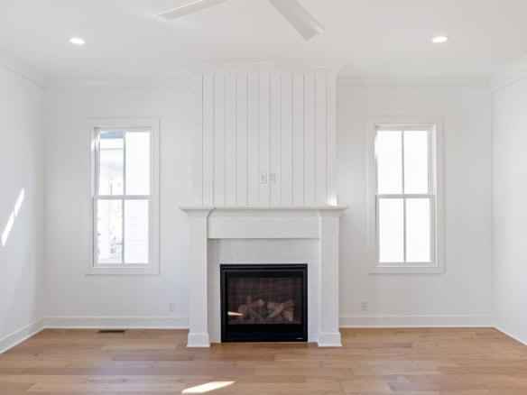 Living room with modern fireplace, white walls, and large windows.