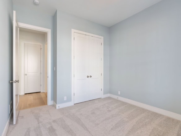 Interior view of a clean, empty bedroom with light blue walls and a closet.