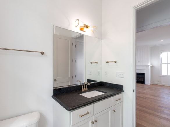 Bathroom vanity with black countertop, mirror, and modern lighting.