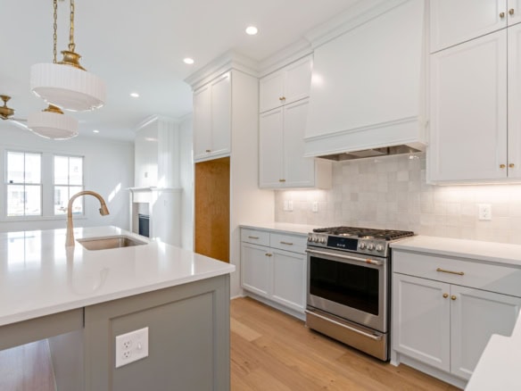 Modern white kitchen with stainless steel stove and island.