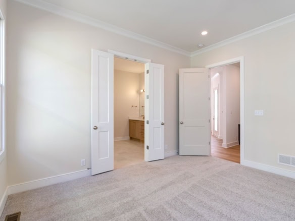 Bright, spacious bedroom with beige walls and plush carpet flooring.