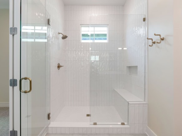Bright white tiled walk-in shower with glass door.