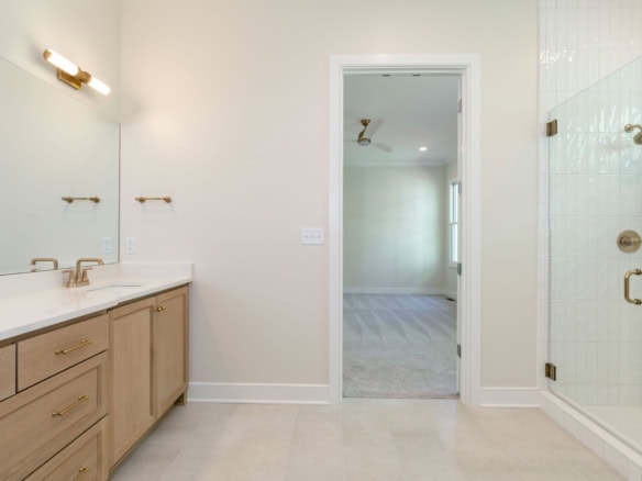 Modern bathroom featuring a glass-enclosed shower and double vanity with gold fixtures.