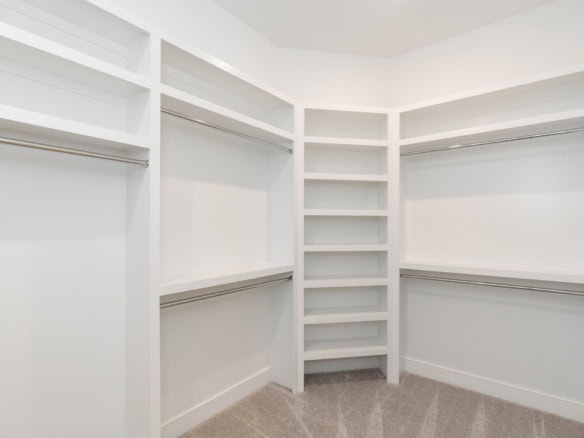Bright white walk-in closet with multiple shelves and hanging rods.