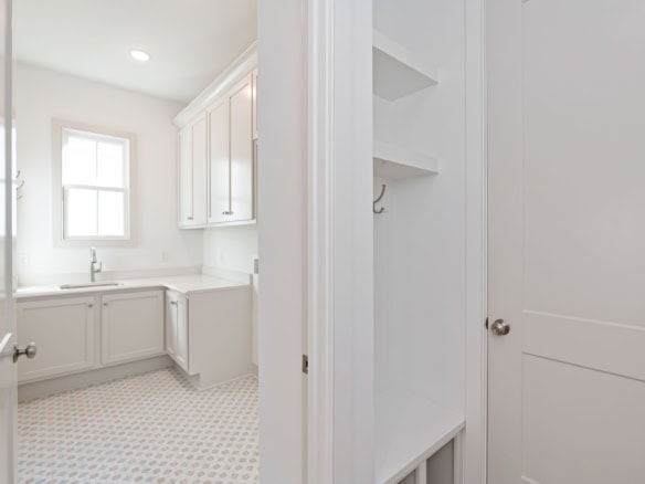 Interior view of a bright, modern laundry room with white cabinets and natural light.