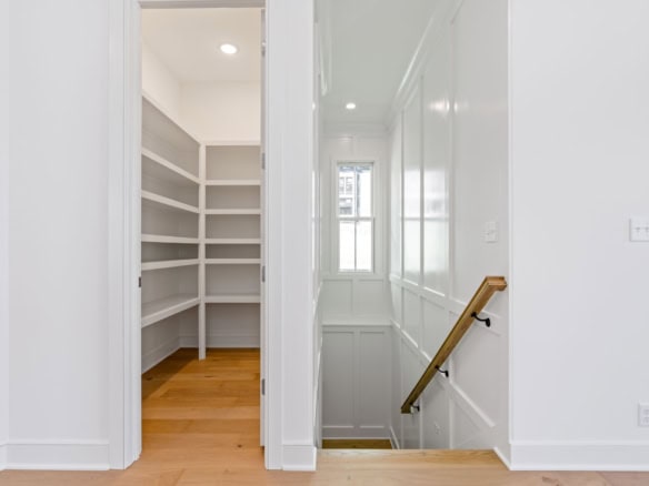 Interior view of a bright, modern home with white walls, built-in shelves, and a staircase.