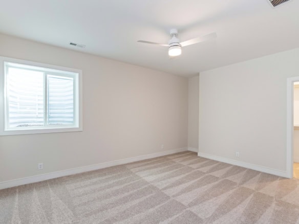 Bright, empty bedroom with white walls, window, and ceiling fan.