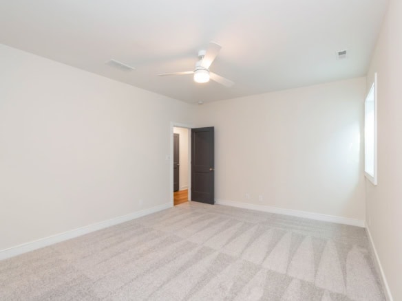 Interior room with white walls, ceiling fan, and window in a residential home.