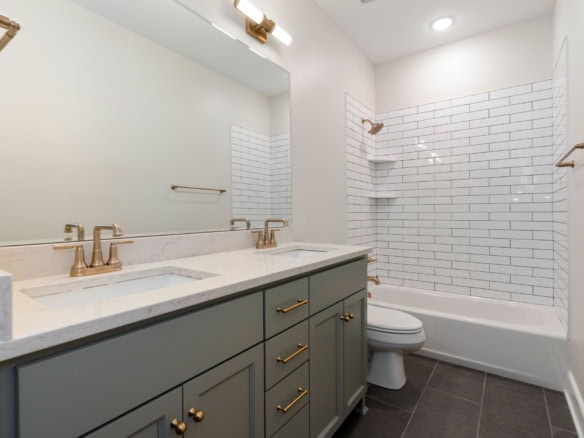 Bathroom with double sink vanity and white tiled shower area.