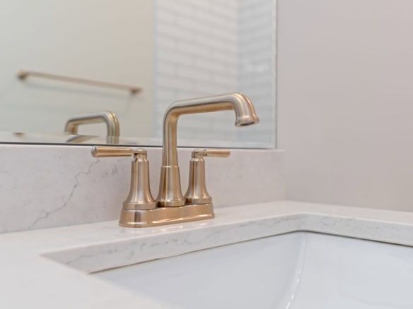 Bathroom sink faucet with marble countertop and mirror in a modern bathroom.