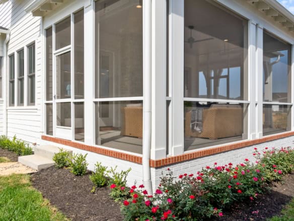 Screened porch with white framing and garden bed at 11530 River Beauty Loop.