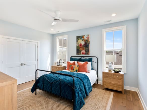Bright bedroom with large windows, modern decor, and cozy bedding.